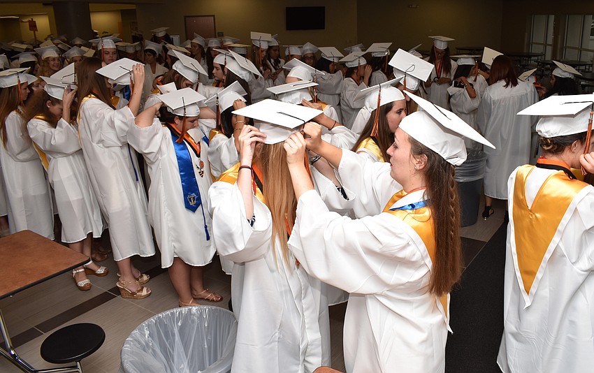 Students helped each other adjust their caps before lining up in the cafeteria before graduation began on June 2 at Sarasota High School.
