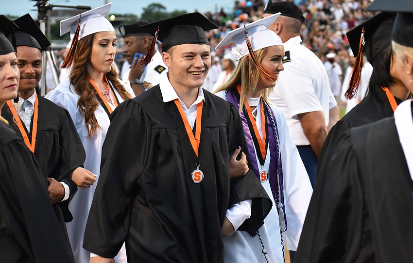 Students enter arm in arm during Sarasota High School graduation at Cleland Stadium at Ihrig Field.