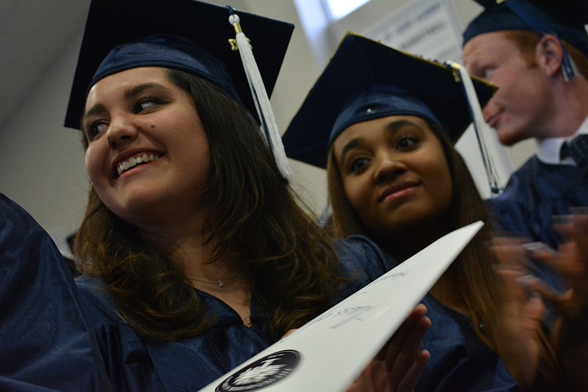 Helena Beltrano, left, claps for the commencement speaker. A future student at Berklee College of Music, she sang 
