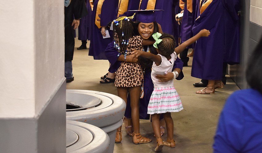 Cellexia Foster hugs her friend’s little sisters before the Booker High School Graduation on June 3 at Robarts Arena.