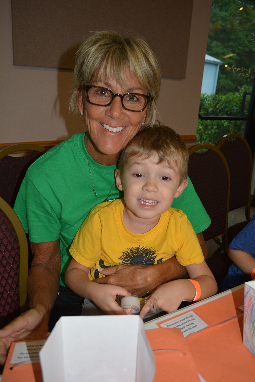Volunteer Shari Medley helps Parker Rhodes, 3, with his craft.