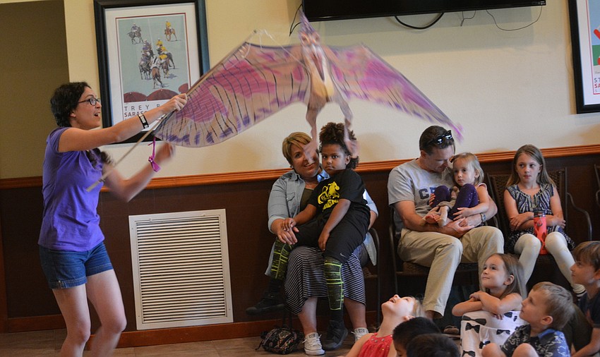 Eliza Engle brings a dinosaur a little closer to her audience.