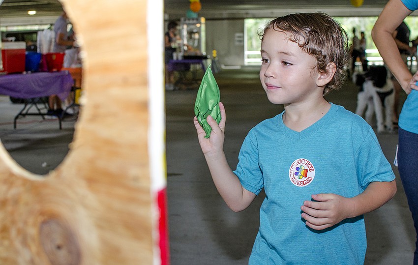 Jake Caraballo plays the bag toss game at the  Doctors Hospital of Sarasota's carnival benefiting the Southeastern Guide Dogs.