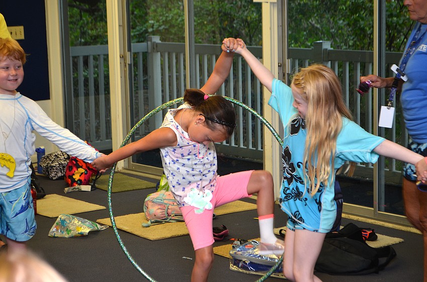 The campers started off the day with an ice-breaker activity. They had to move the hula hoop around the circle without breaking their hands apart. Here, Stevie Schlossberg tries to move the hula hoop over her head with the help of Makenna Marks.