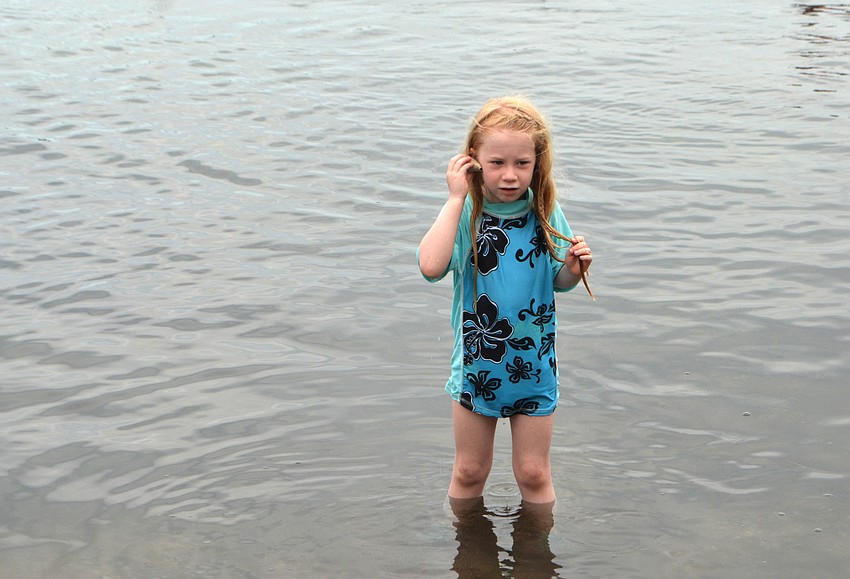 Makenna Marks listens for the ocean in a shell she found.