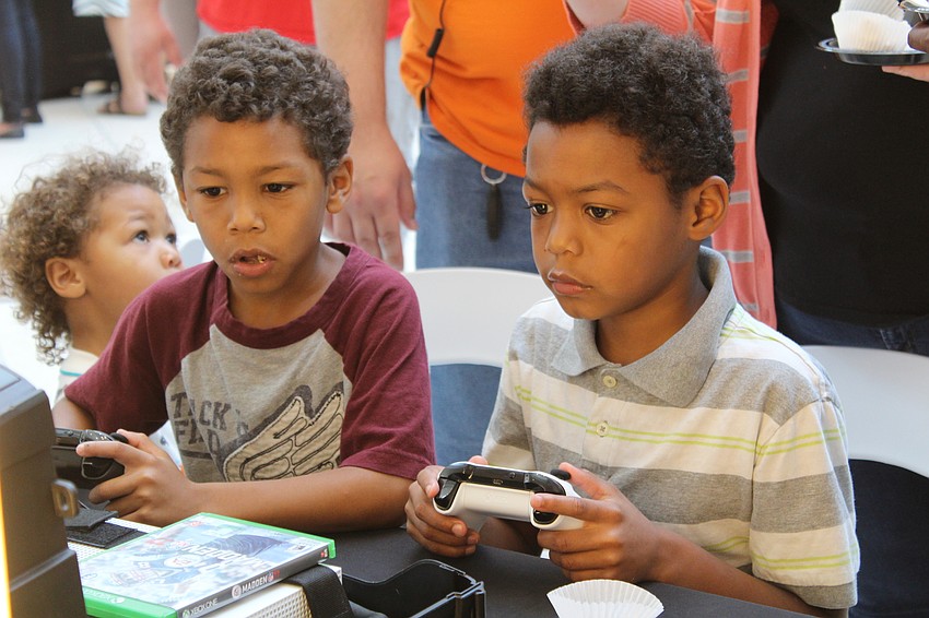 Sarasota's Rylan and Travis White play video games during Dad's Day at The Mall at University Town Center.