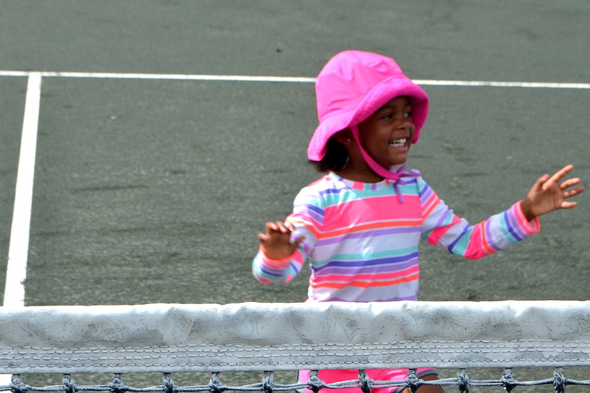 Sofia Grace Harris is all smiles as she races her tennis coach to the net.