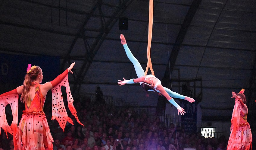 Grace Milton performs on the Aerial Hammock, with Alice Hafner (left) and Lillian Hafner (right) on the stilts.