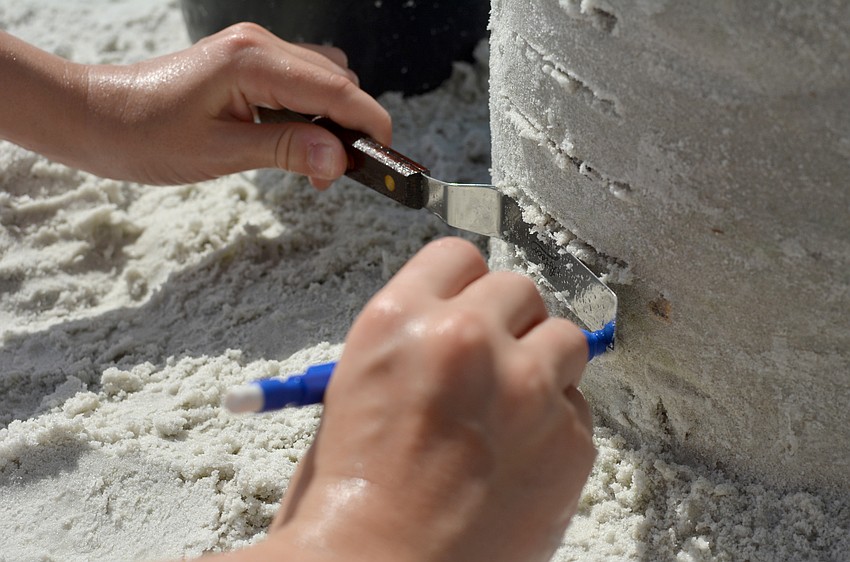 Makena Jenkins add texture to her dual-turret sand castle.