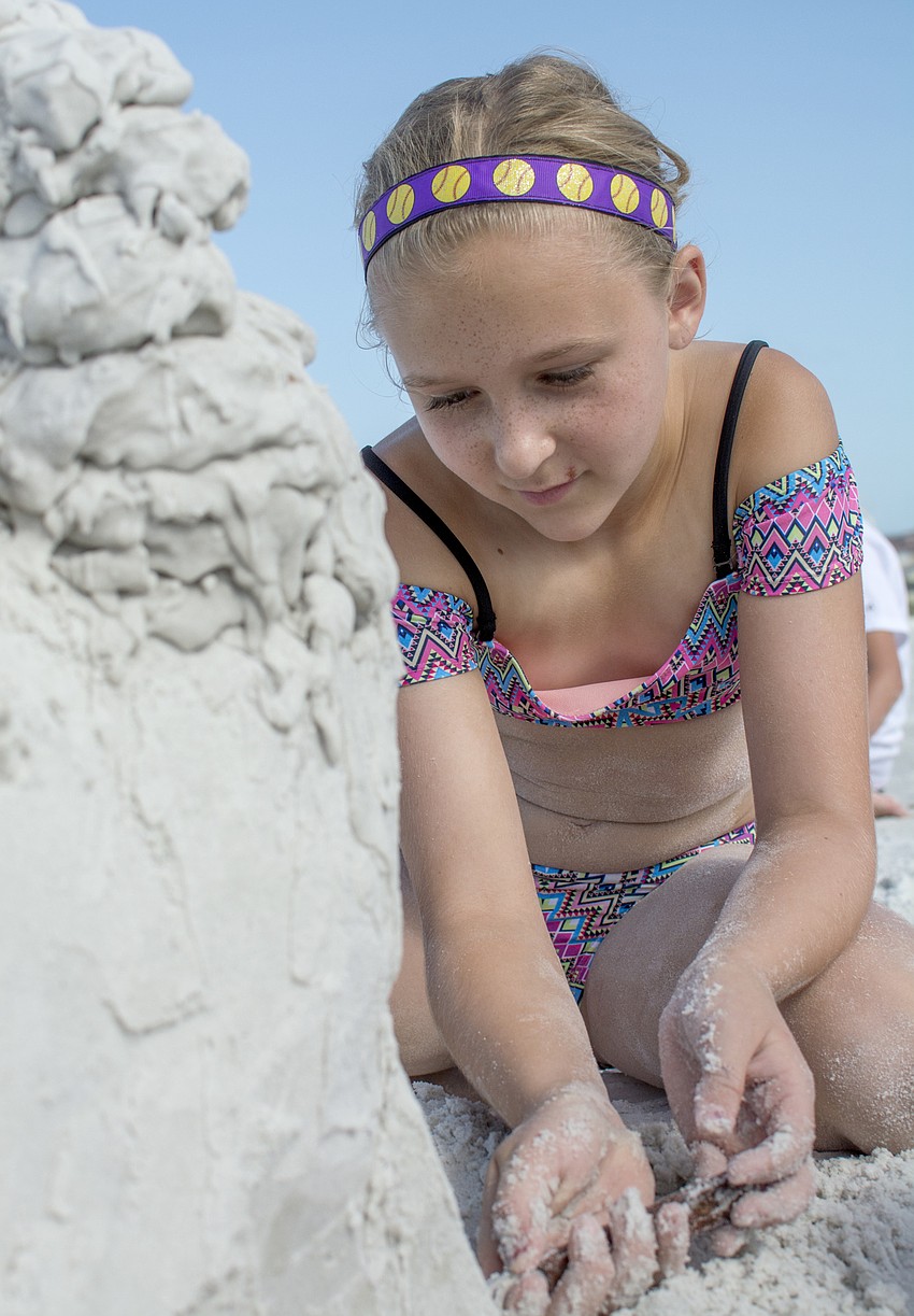 Sierra Lipton carefully scrapes sand from her sculpture of Pikachu.