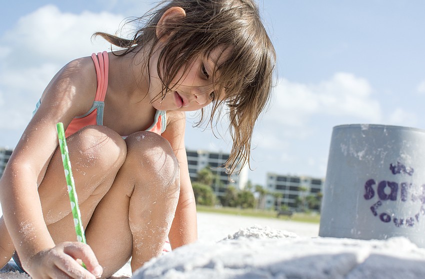 Evelyn Bunker adds texture to her sand turtle, which she named Emma.