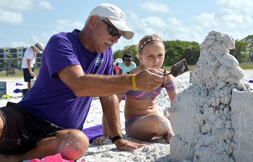 Bill Knight helps Sierra Lipton plan how to shape her sand sculpture of Pikachu.