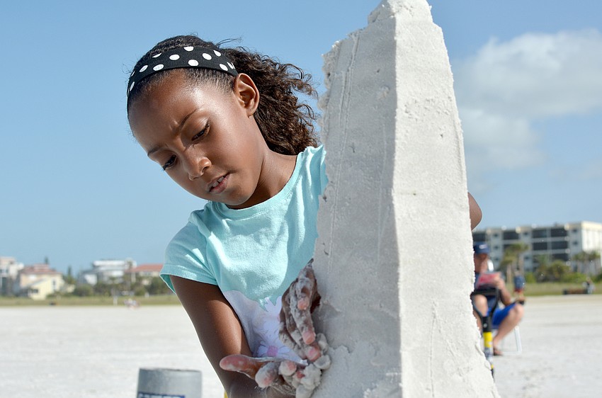 Lyric Willis works on her sand sculpture of the Eiffel Tower.