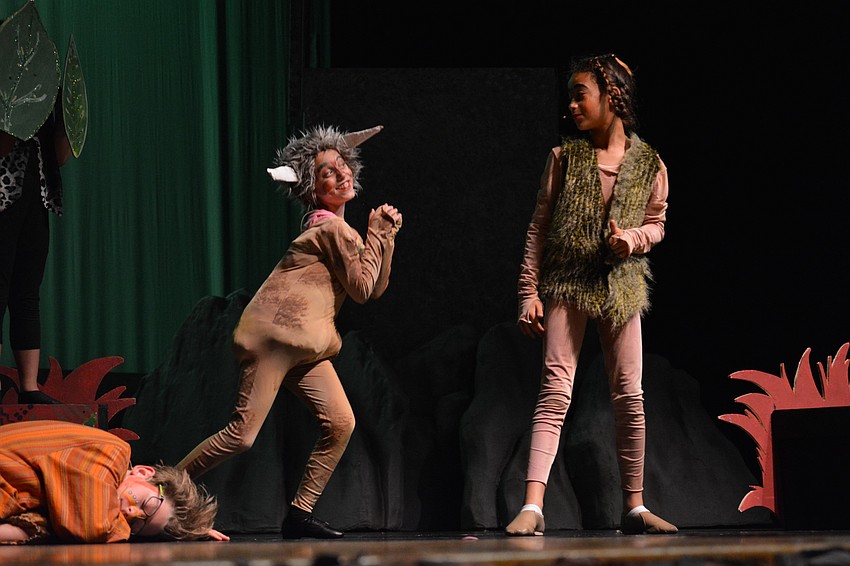 Pumbaa the pig (Addison Schoenfield) begs Timon (Yaira Spears) if they can keep the lion cub they find sleeping.