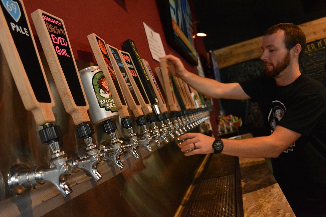 Beer tender Tyler Robideau fills up a glass during Naughty Monk&#39;s official grand opening of the brewery June 22.