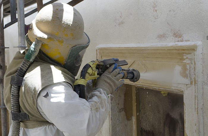 Izzy Rodriguez, a worker with ADS Environmental Services, washes away stucco and paint to reveal the building's original color.