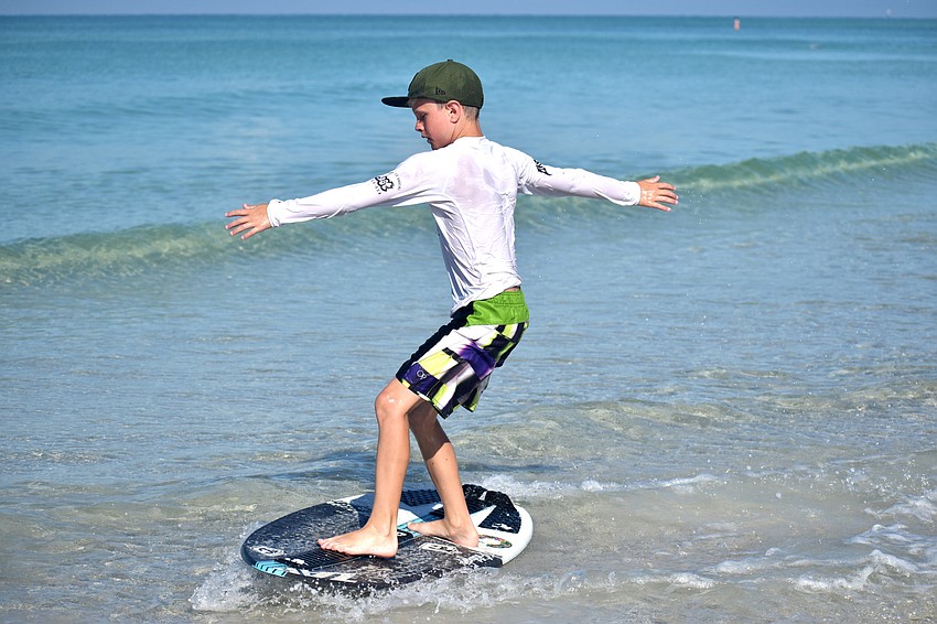 George West rides his skimboard along the shore of Lido Beach.