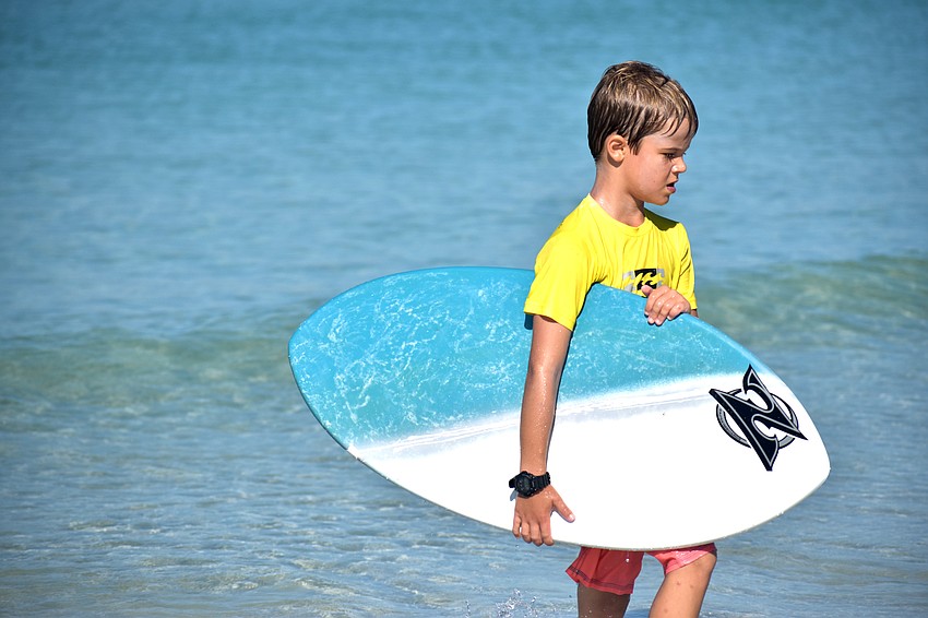 Stirling McLoughlin carries his skimboard to shore.