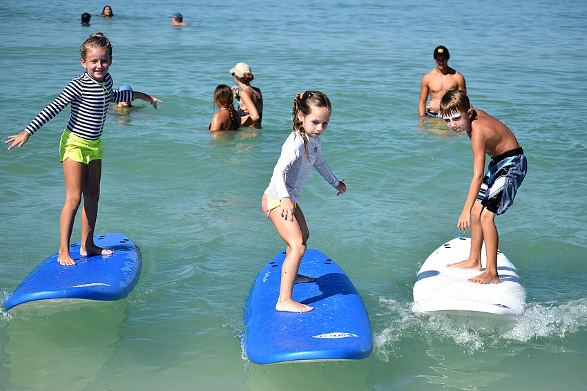 Mia Freeman, Gigi Tuffile and Connor Helrigle test their surfing skills during Sarasota County’s Skim, Surf and Paddle Camp on June 28.