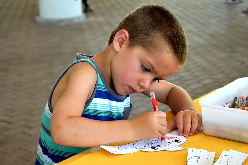 Luke Young concentrates while coloring a shark headband.