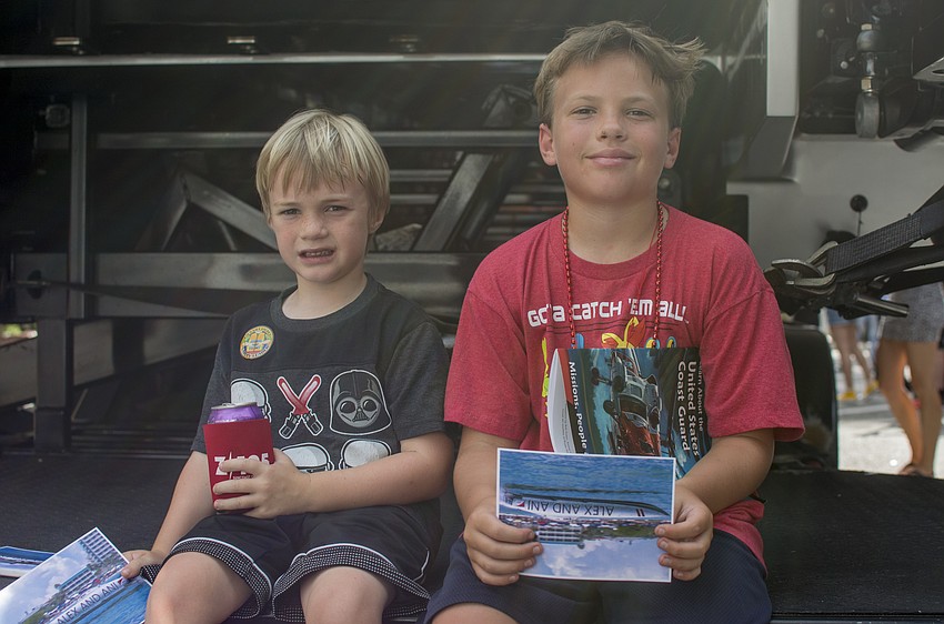 Cole and Cody Schrader sit near one of the boats set to participate in the Sarasota Powerboat Grand Prix.