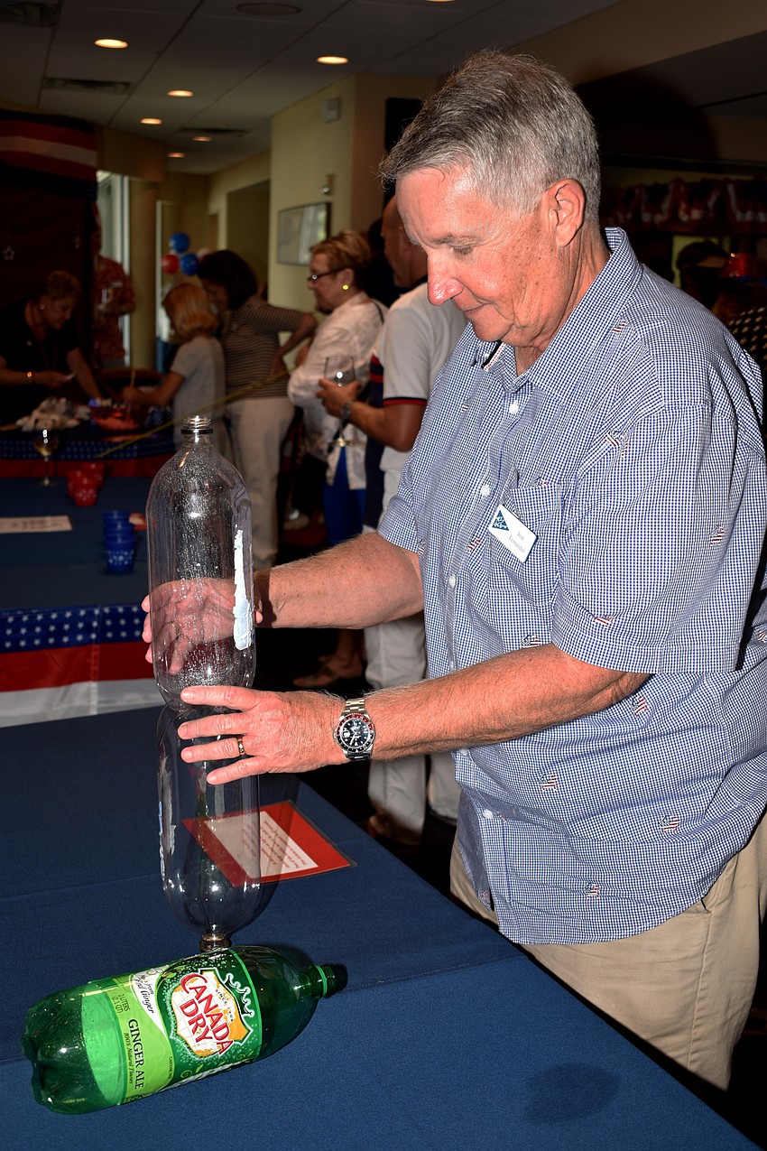 Jose Fernandez tries to balance liters of soda on top of each other during Bird Key Yacht Club’s July Fourth celebration.
