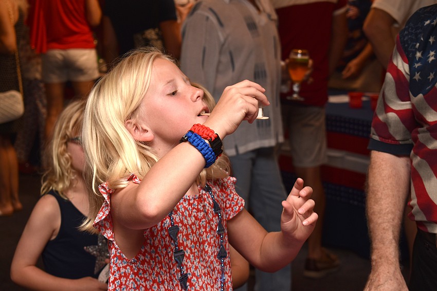 Elli Burkholder tries to balance dice on a popsicle stick during Bird Key Yacht Club’s July Fourth celebration.