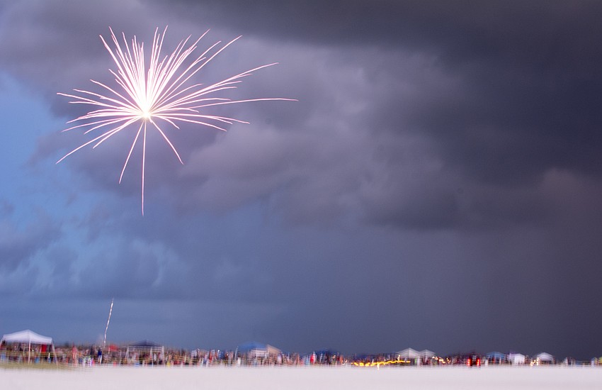 Nearby condos light off fireworks near Siesta Key Public Beach as a storm front approaches.