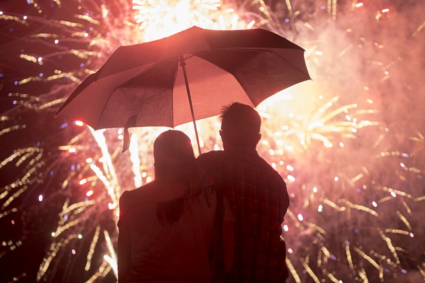 Jackie Smith and Mike Garrett watch the finale of the Siesta Key fireworks from under an umbrella.