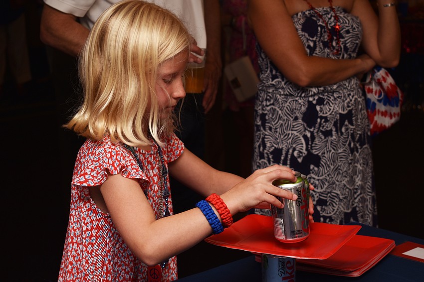 Elli Burkholder stacks Diet Coke cans on paper plates to make a pyramid during Bird Key Yacht Club’s July Fourth celebration.