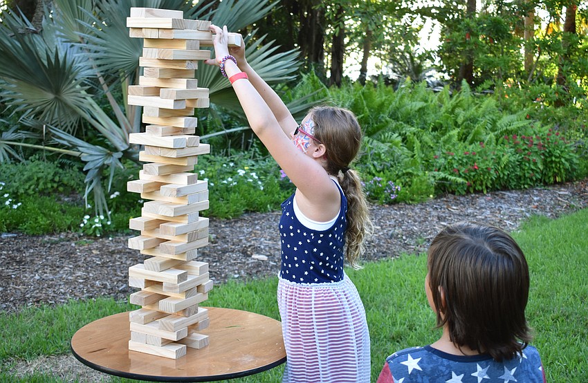 Ceylon Vanston plays Jenga while her brother Nathan Vanston observes.