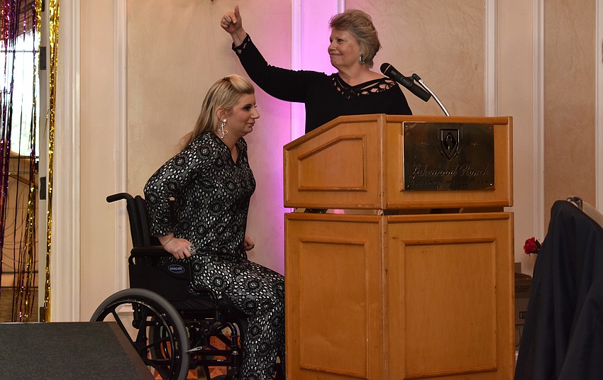 Alice Bozza points to her daughter, Samantha Bozza, before she stands up to welcome guests to her event.