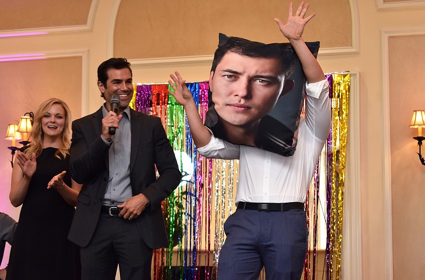 Martha Madison and Jordi Vilasuso laugh as Christopher Sean shows off the auction item that featured a photo of his face: an oversize throw pillow.