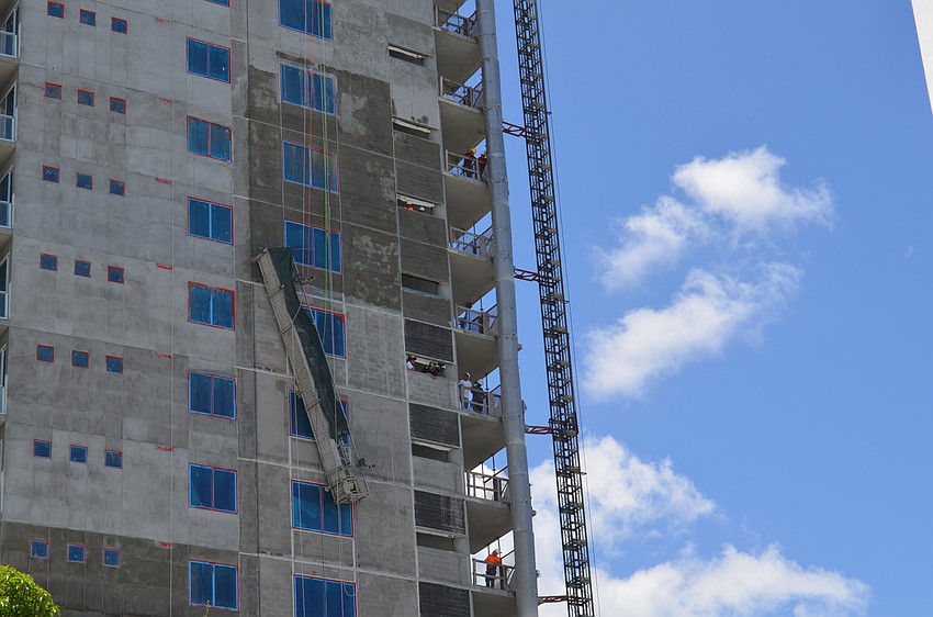 Construction workers look on as crews rescue a man trapped along the side of a Palm Avenue high-rise.