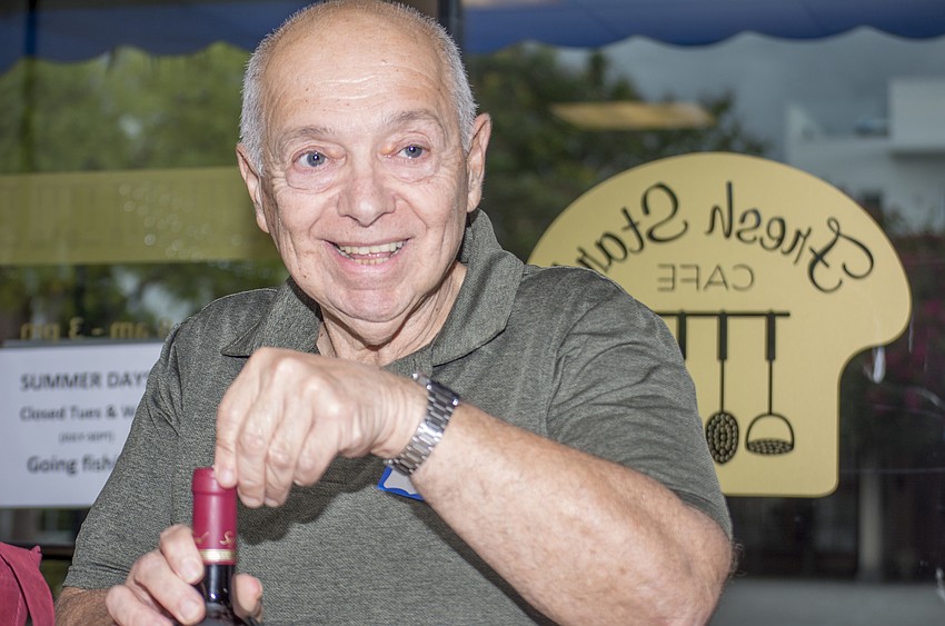 Bill Haiby uncorks a bottle of wine during Temple Emanu-El's wine tasting event.