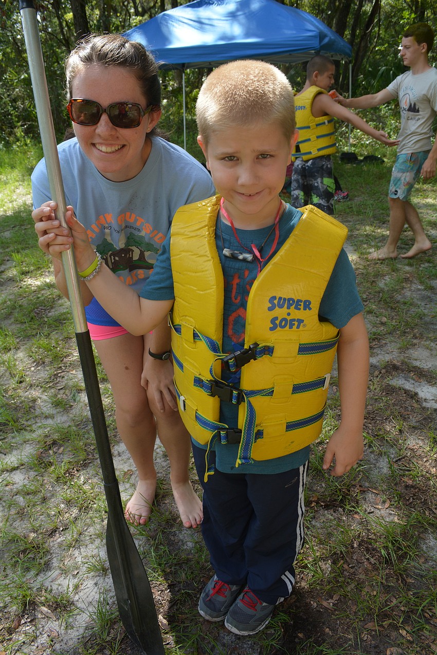 Counselor Jenna Baines gets Dallas Adams, 9, ready for his canoe voyage.