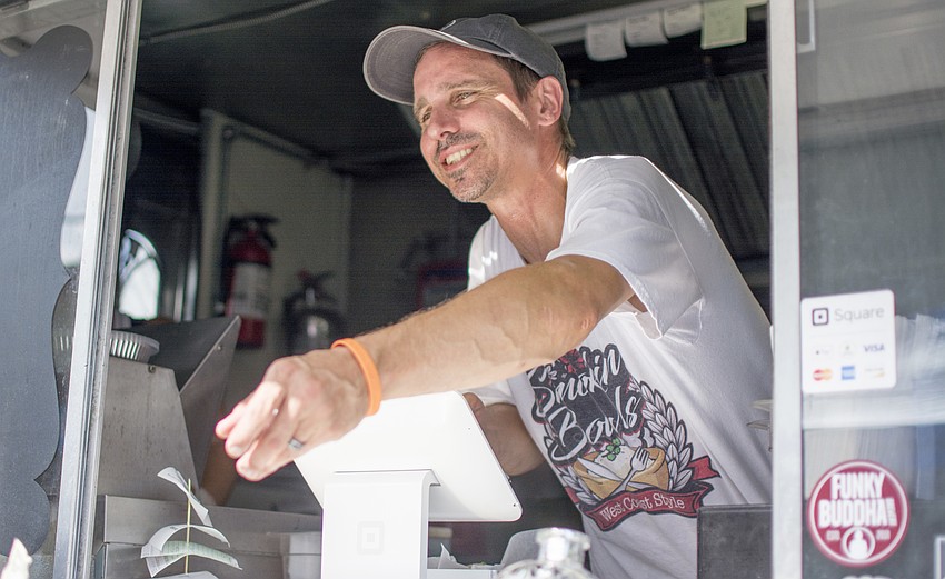Brian Lairby of Smoking Bowls food truck smiles after serving a costumer at the one-year anniversary food truck rally at JDub's Brewing Company.