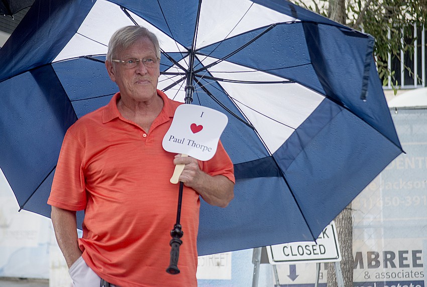 Tom Welicki stands under his umbrella during the renaming ceremony. City staff passed out fans honoring Thorpe.