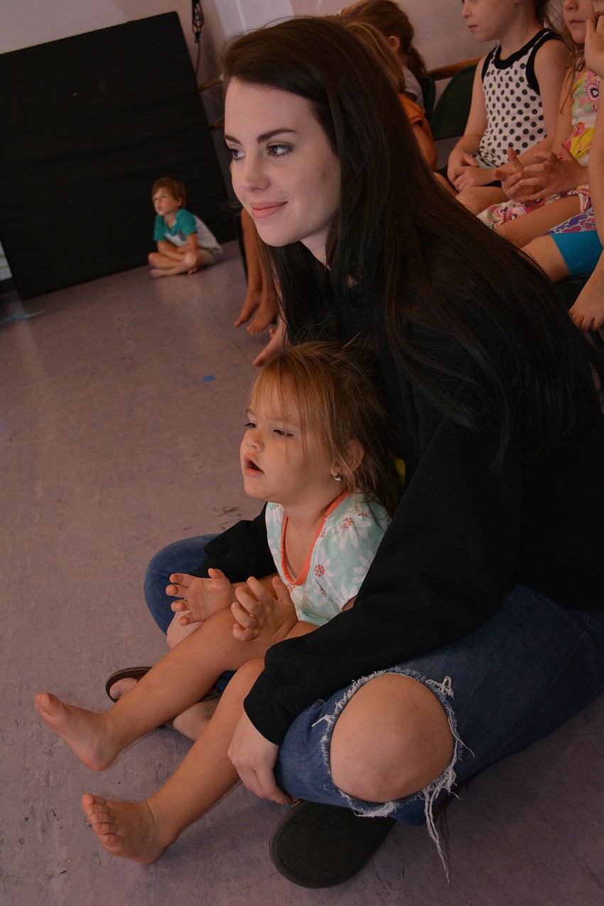 Preschool camper Macie Gore, 2, watches the show from the lap of counselor Kylee McKinney. Macie loves clapping to the songs.