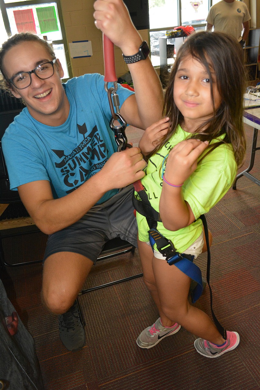 Counselor Nathan Gross readies Layla Baines, 7, of Willis Elementary, to climb the rock wall.