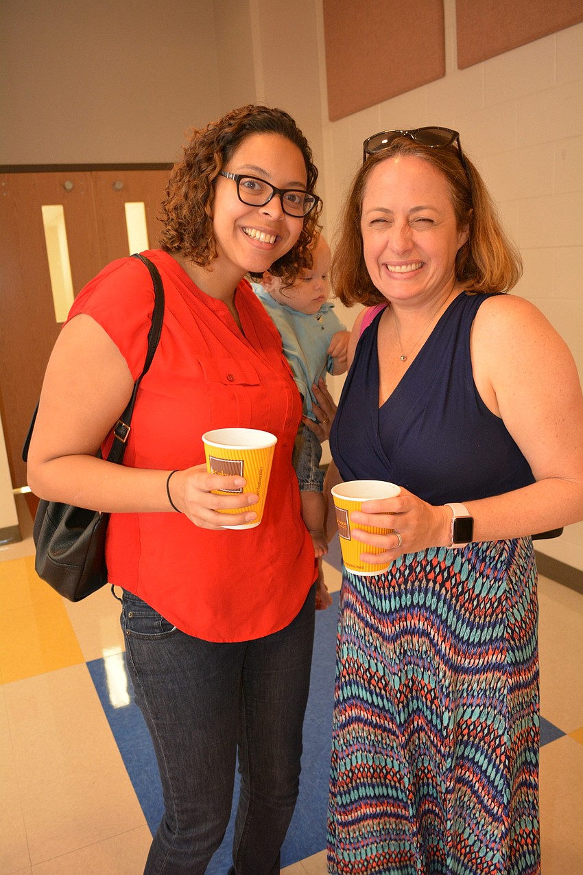 Amaris Baumgard, with her son, Samuel, chats with Maggie Mooney-Portale after dropping their children off at their classrooms.