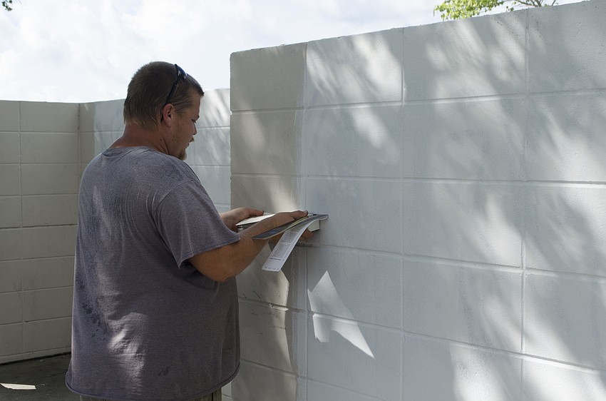 County worker Scott Crouch works to cover up the graffiti and find the right paint color to further erase the marks.