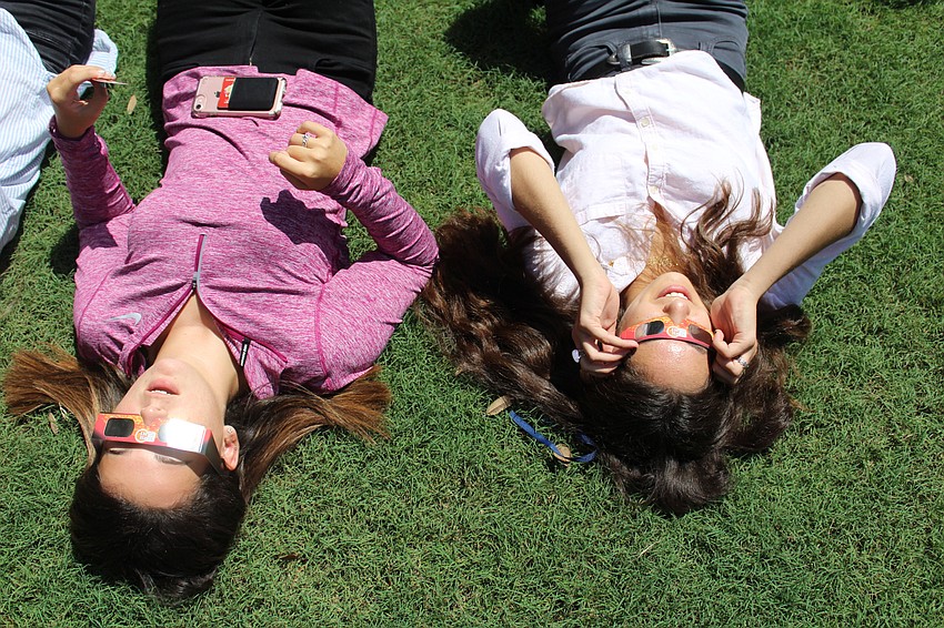 Out-of-Door Academy seniors Evalee Mason and Nora Altajar take a look at the solar eclipse in ODA's quad.