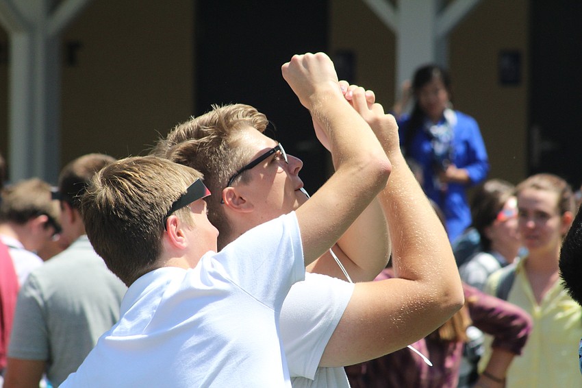 Out-of-Door Academy seniors Marius Bschorer and Kevin Bernet get the hang of their cell phone filters during the solar eclipse.
