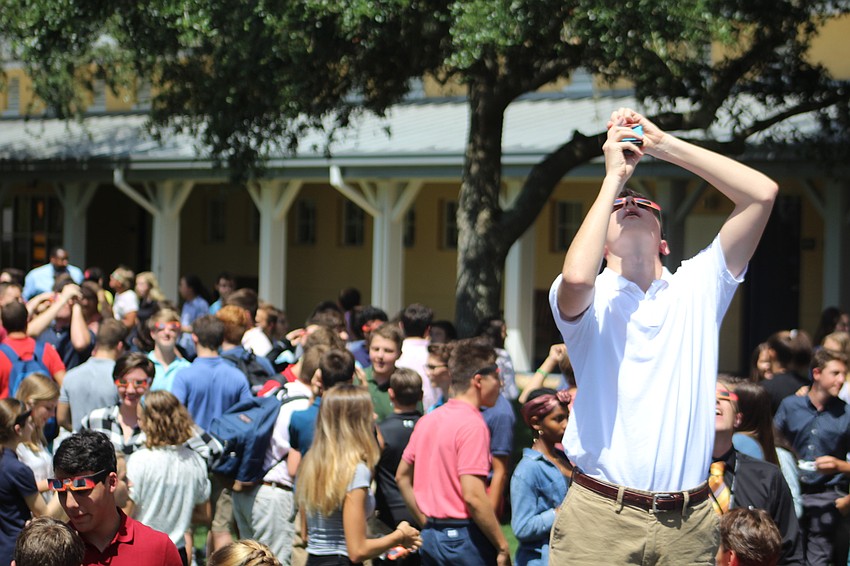 Out-of-Door Academy junior John Floersheimer tries to get a photo of the solar eclipse while others view it in ODA's quad.
