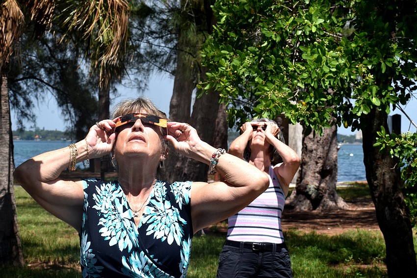 Joyce Hooey and Allison Hively shield their eyes with protective glasses.