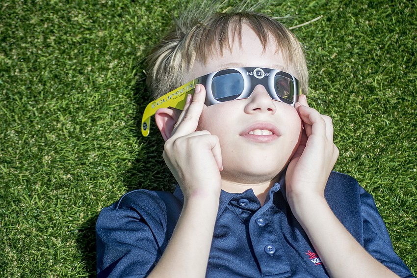 Southside Elementary Student Kyle Kenny watches the eclipse through solar eclipse viewing glasses.