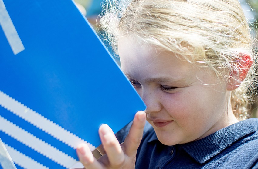 Zoey Polk uses a a shoe box viewing device to watch the solar eclipse.