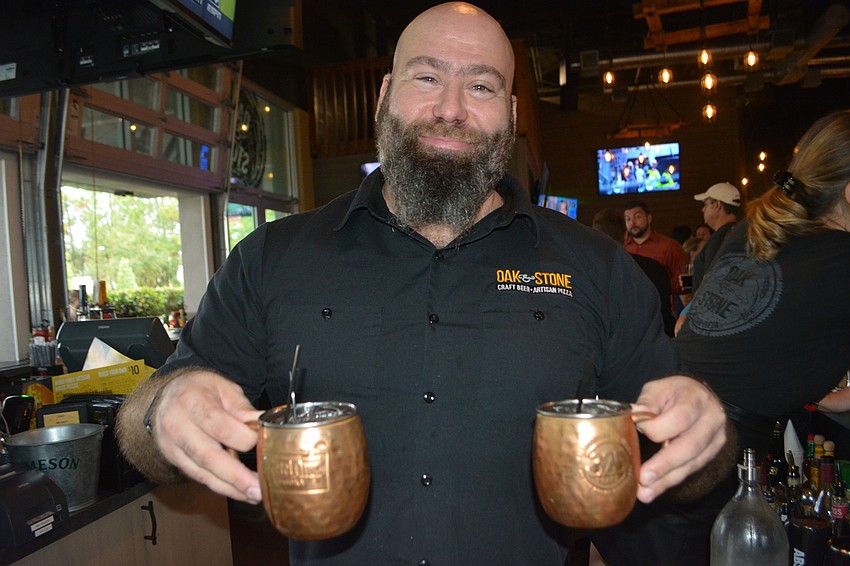 Oak & Stone Bar Manager Christian Seymour delivers a pair of Crafty Mules served in copper mugs.