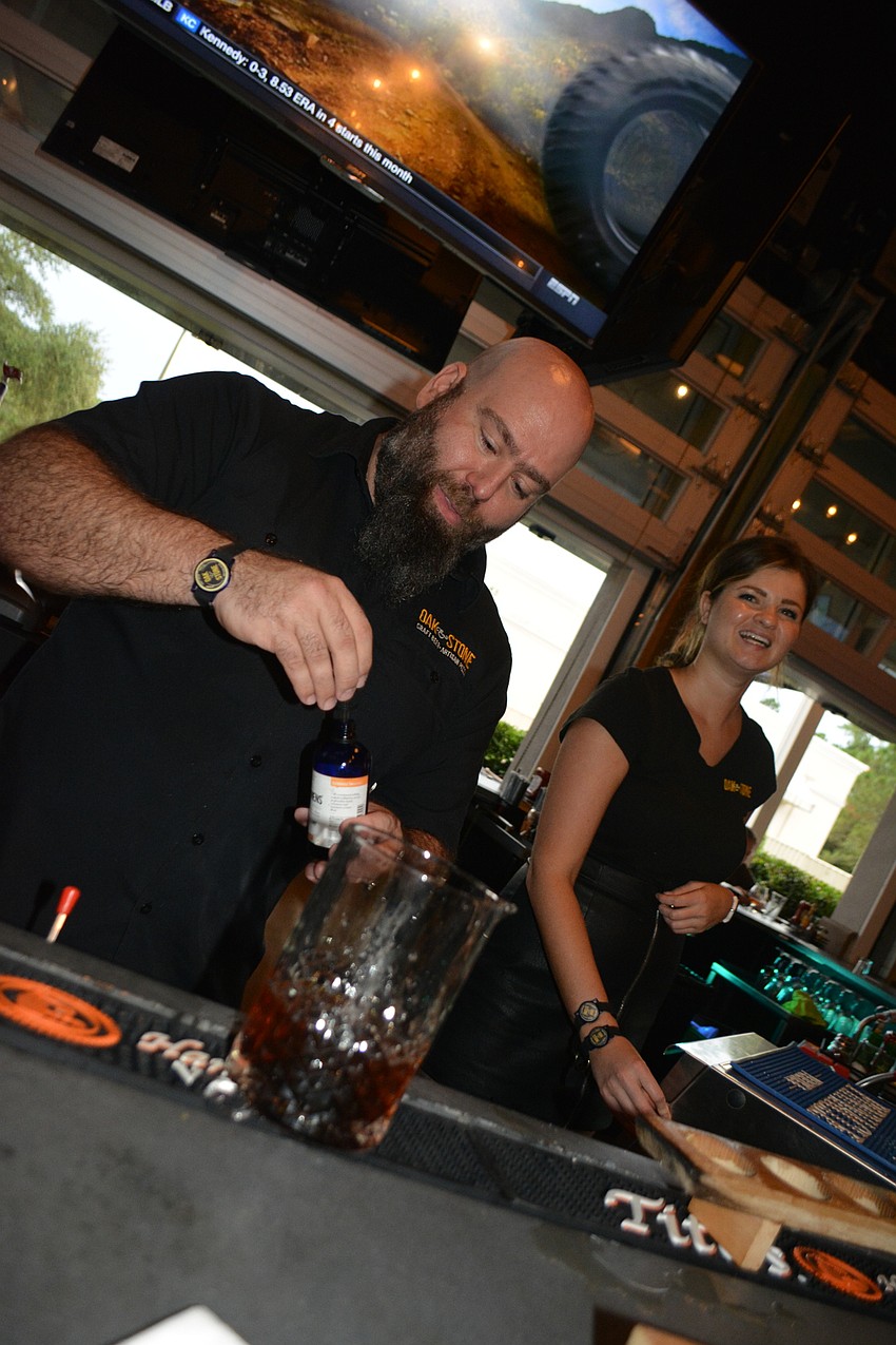 Bar Manager Christian Seymour uses an eyedropper to deliver bitters as Manager Alex Scott looks on.
